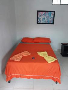 een bed met oranje lakens en gele shirts erop bij Hostal Flor del Ariari in Puerto Caldas