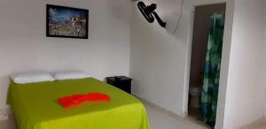 - une chambre dotée d'un lit vert avec une fleur rouge dans l'établissement Hostal Flor del Ariari, à Puerto Caldas