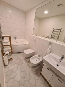 a bathroom with a sink and a toilet and a tub at Sea View Apartment Elija in Šventoji