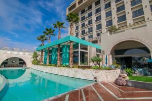 un hotel con piscina frente a un edificio en Torre Lucerna Hotel Ensenada en Ensenada