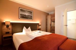 a hotel room with a bed with an orange blanket at Lindenberger Hof in Lindenberg im Allgäu +64 photos