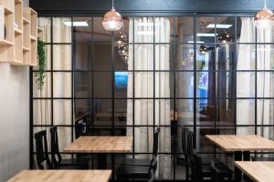 a restaurant with wooden tables and chairs and a glass wall at Hotelli Loimu in Raisio