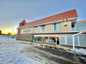 a building with a parking lot in front of it at Ramada by Wyndham Whitecourt in Whitecourt