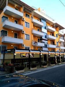a large apartment building with a restaurant in front of it at Aparthotel Shkodra in Durrës