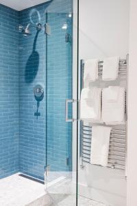 uma casa de banho com uma cabina de duche em vidro com azulejos azuis em Best Bower em Portland