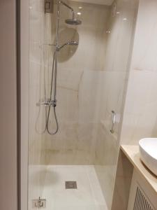 een douche met een glazen deur naast een wastafel bij La Perle d´Ostende in Oostende