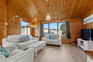 a living room with two couches and a tv at Bream Bay Sands - Ruakaka Holiday Home in Ruakaka