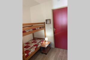 een kleine slaapkamer met een stapelbed en een rode deur bij Logement 4/6 personnes à la montagne avec piscine in Saint-Sorlin-dʼArves