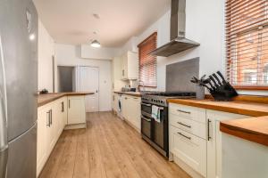 cocina grande con armarios blancos y suelo de madera en Spacious Contractor House for Large Groups - Private Parking, en Northampton