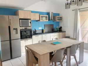 a kitchen with a table with chairs and a refrigerator at Maison Barcarès 4 à 7 personnes climatisée in Le Barcarès