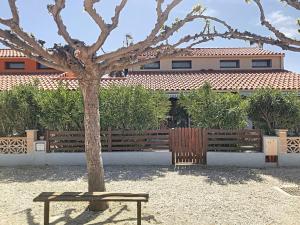 a tree and a bench in front of a building at Maison Barcarès 4 à 7 personnes climatisée in Le Barcarès