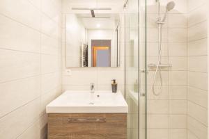 een witte badkamer met een wastafel en een douche bij AlsaceTime, CENTRE Parking gratuit, TRAM WIFI, Fibre Orange, espace de travail in Straatsburg +20 foto's