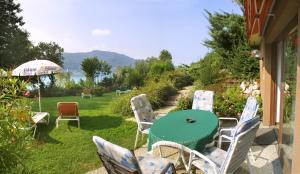 eine Terrasse mit Stühlen, einem Tisch und einem Sonnenschirm in der Unterkunft Ferienwohnungen Salmen in Pörtschach am Wörthersee
