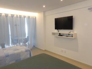 a living room with a tv on a wall at HOTEL GARVEY Quarto 321 in Brasilia