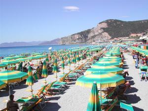 una playa llena de sombrillas verdes y amarillas en Casa Vacanze Isophylla en Finale Ligure