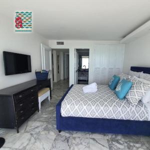1 dormitorio con 1 cama con almohadas azules y TV en Hermosos Apartamentos Frente Al Mar en San Andrés