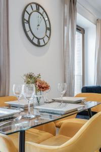 a table with chairs and a clock on the wall at LillyRose Serviced Apartments - St Albans City Centre in Saint Albans