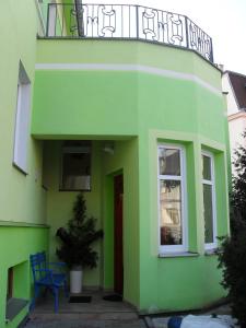 a green building with a balcony and a blue chair at Pension Rak in Karlovy Vary