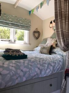 a bedroom with a bed with purple comforter and a window at Shepherds Hut with Hot Tub in Lymington