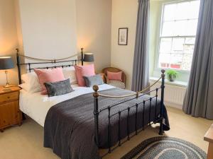a bedroom with a large bed with pink pillows at Miners Cottage in Middleton in Teesdale