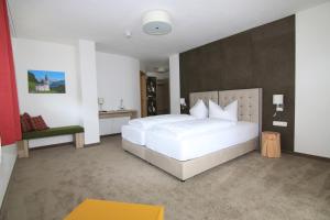 ein Schlafzimmer mit einem großen weißen Bett und einem Stuhl in der Unterkunft Alpinhotel Berchtesgaden in Berchtesgaden