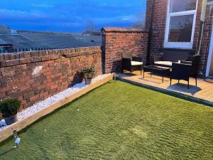 a backyard with a lawn and a brick wall at KAREN-K HOLIDAY HOME by Edl Ventures Ltd in Oldham