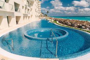 a swimming pool next to a building and the ocean at Emporio Cancun - Buy All Inclusive Option in Cancún