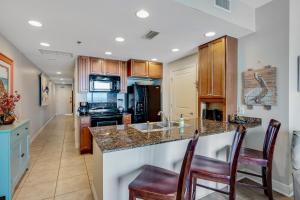 a kitchen with a counter and chairs and a sink at Sterling Breeze 903 in Panama City Beach