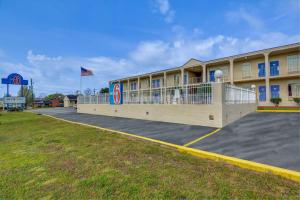 a hotel building with a flag and a parking lot at Motel 6-Americus, GA in Americus
