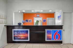 una zona de espera con una pared de color naranja y un cartel en Motel 6-Americus, GA, en Americus