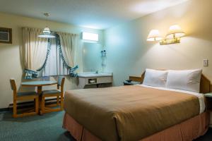 um quarto de hotel com uma cama e uma mesa e cadeira em The Ranchland Inn Kamloops em Kamloops