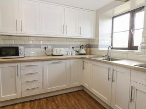 a white kitchen with white cabinets and a sink at Hayloft in Staintondale +42 photos