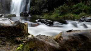 una cascada en medio de un río con rocas en Cradle Gateway Chalets, en Moina