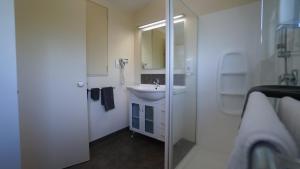 Baño blanco con lavabo y espejo en Whangarei Central Holiday Park en Whangarei