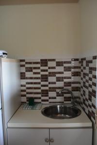 a kitchen with a sink and a tiled wall at Mamas Reas in Káto Spílaion