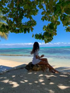 a woman sitting on a rock on the beach at Moorea Island Beach Hotel in Moorea