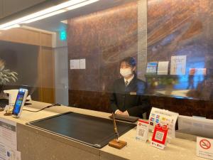 a woman wearing a mask sitting at a counter with a practition at Hotel Bijiko in Bibai
