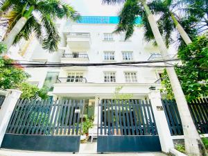 a white building with palm trees in front of it at Pearl Service Apartment in Ho Chi Minh City