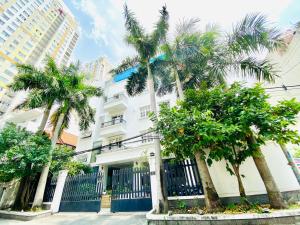 a white building with palm trees in front of it at Pearl Service Apartment in Ho Chi Minh City