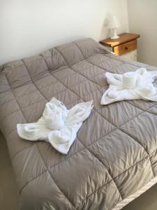 Una cama con dos toallas blancas encima. en Departamento Centrico VDL en Puerto Madryn