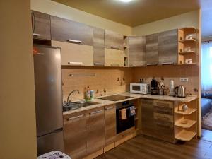 a kitchen with wooden cabinets and a stainless steel refrigerator at Thermal apartman in Hajdúszoboszló