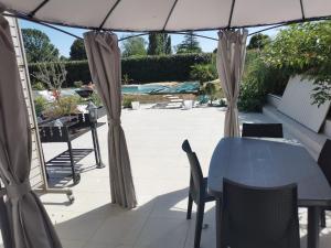 Un patio con una mesa y sillas y una sombrilla. en PETIT COIN DE CHARME, en Seyresse