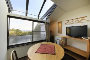 下田市にあるWelcome Inn SunnyStepsのテーブルと大きな窓が備わる客室です。