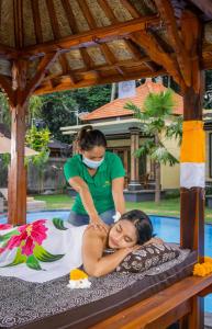 Una donna che riceve un massaggio da una donna sul letto di Abhirama Villas by Supala ad Ubud