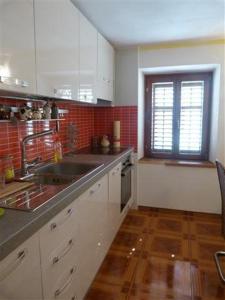 cocina con armarios blancos, fregadero y ventana en Apartments Zukanovic, en Fažana