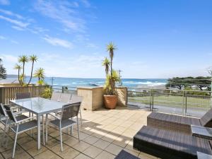 a patio with a table and chairs and the ocean at Apartment 11 Pacific Apartments in Lorne
