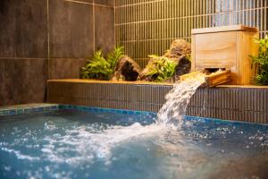 a pool with a water fountain in a garden at Cabin & Capsule Hotel J-SHIP Osaka Namba in Osaka
