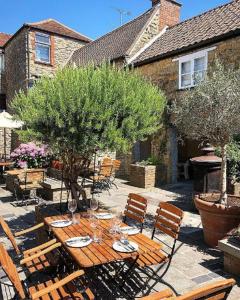 una mesa de madera y sillas con copas de vino. en The Plume of Feathers, en Sherborne