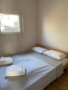 Bett in einem Zimmer mit zwei Kissen und einem Fenster in der Unterkunft ApartmaniZvezdara in Zvezdara