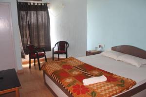 a bedroom with a bed with two chairs and a window at Arya Beach resort in Mandarmoni